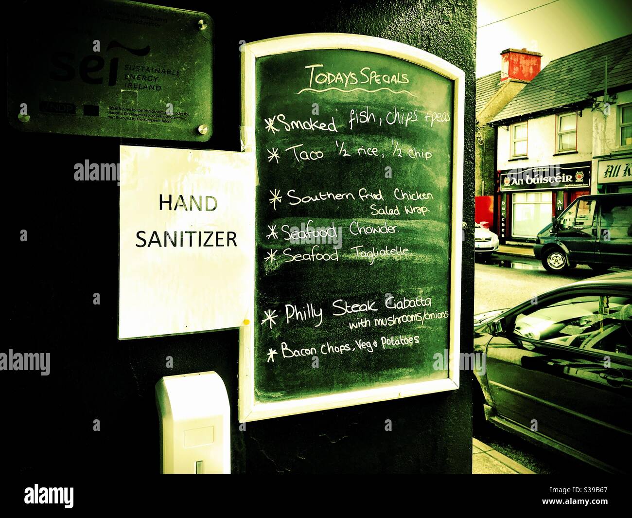 Il menu del caffè mostra le specialità del giorno con dispenser di disinfettante per le mani durante la pandemia di Covid19. Contea di Donegal, Irlanda Foto Stock