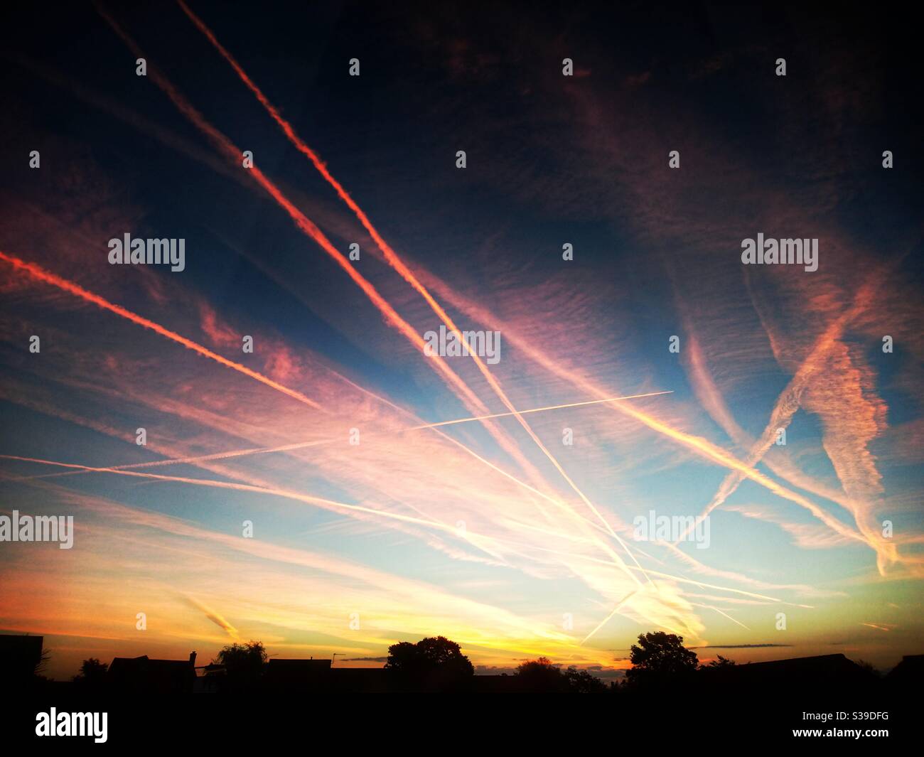 Un meraviglioso e vibrante cielo al tramonto con un sacco di contrails aerei. Foto Stock