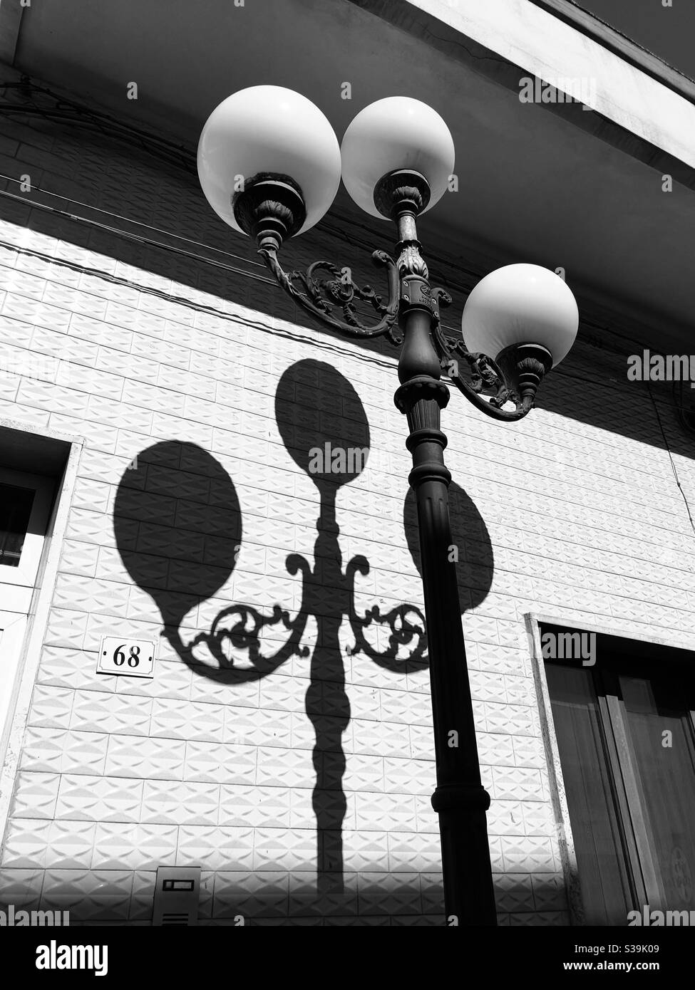 Tre globi lampada da strada e ombra su muro di mattoni Foto Stock