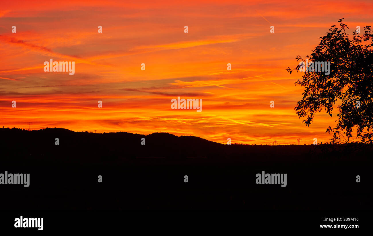 un cielo ardente, un tramonto nel cielo serale mostra nuvole rosse, colori luminosi e brillanti, un momento mozzafiato, sorprendente e affascinante Foto Stock