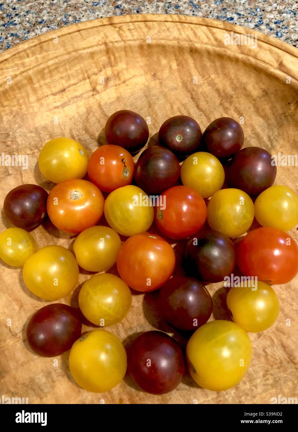 Una varietà di pomodori colorati di primo apparire in una ciotola di legno. Foto Stock