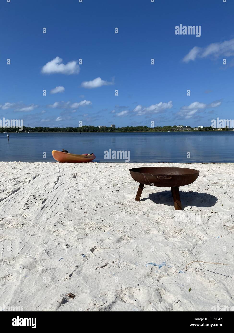 Fossa del fuoco e pagaia su sabbia bianca con vista di acqua di baia blu - Immagine stock catturata con smartphone