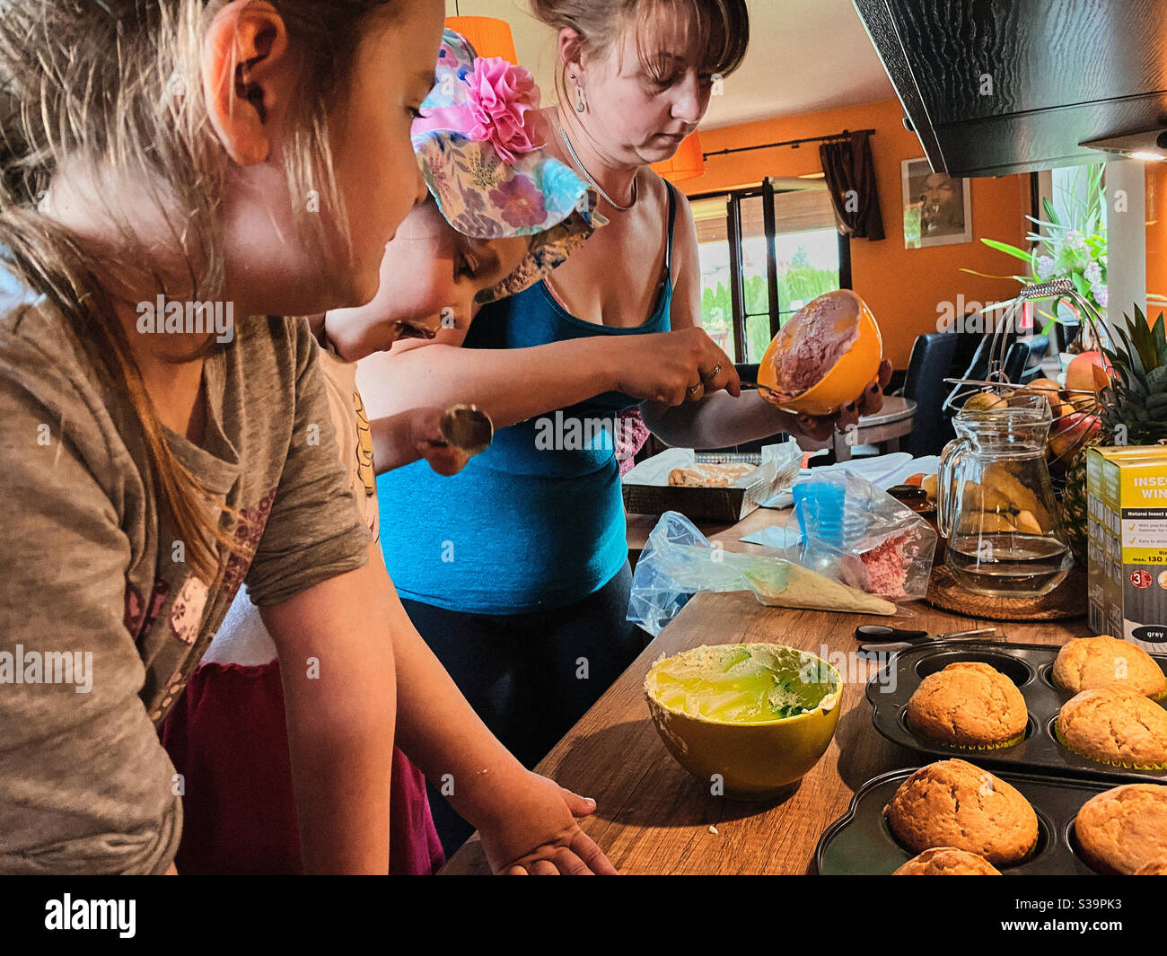 Gruppo di bambini che cuocce, prepara ingredienti, condimenti, spolverate per decorare i biscotti. I bambini imparano a cucinare, lavorando insieme in cucina a casa Foto Stock
