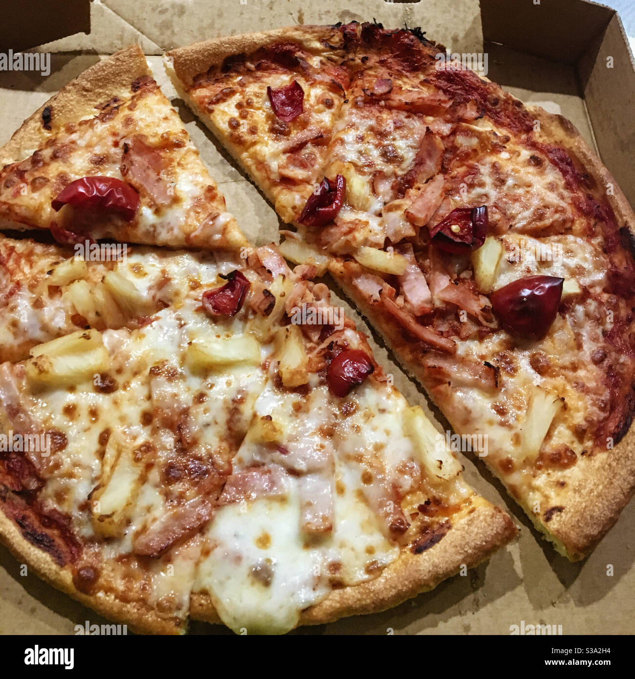 Fast food, pizza da asporto in scatola di cartone, coperto di mozzarella, capsicum rosso e ananas, caldo e pronto a mangiare, yum! - Immagine stock catturata con smartphone