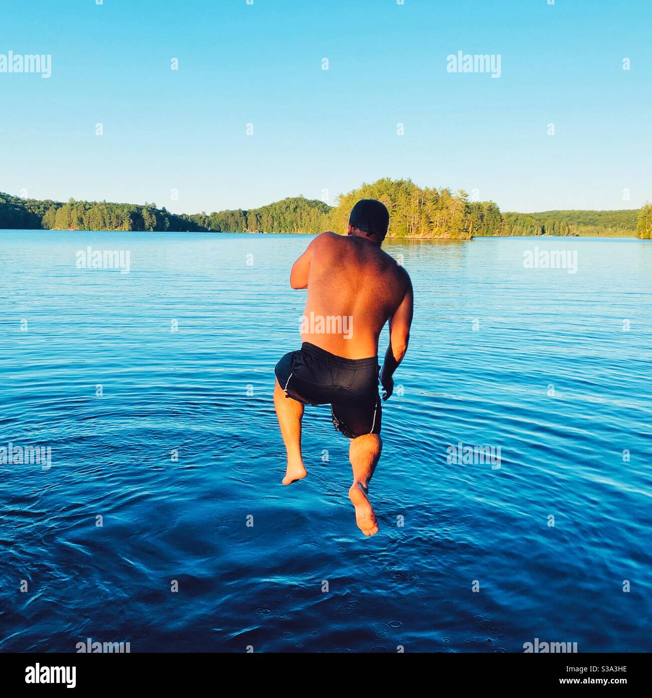 L'uomo saltando nel lago Foto Stock
