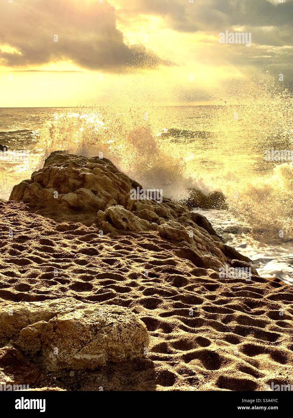 Spiaggia colorata di seppia e onde che si infrangono sulle rocce Foto Stock
