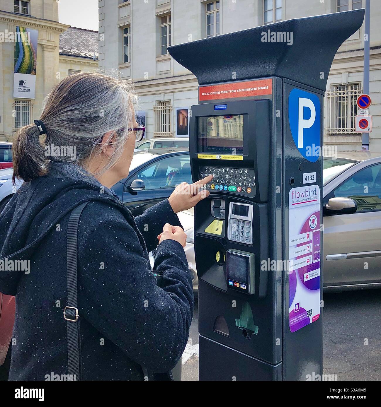 Donna che inserisce i dati di immatricolazione dell'auto presso la biglietteria automatica del parcheggio - Francia. Foto Stock