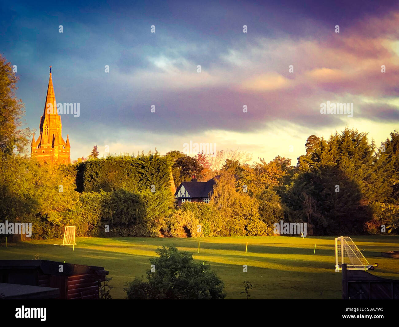Vista su un campo da gioco scolastico con una guglia della chiesa oltre la mattina presto. - Immagine stock catturata con smartphone