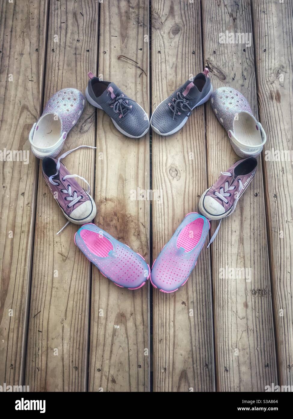 Scarpe da ragazza disposte a forma di cuore su portico in legno estate Foto Stock