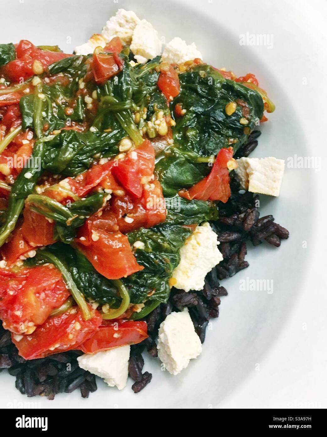 Pomodoro e spinaci con tofu su riso nero. Foto Stock