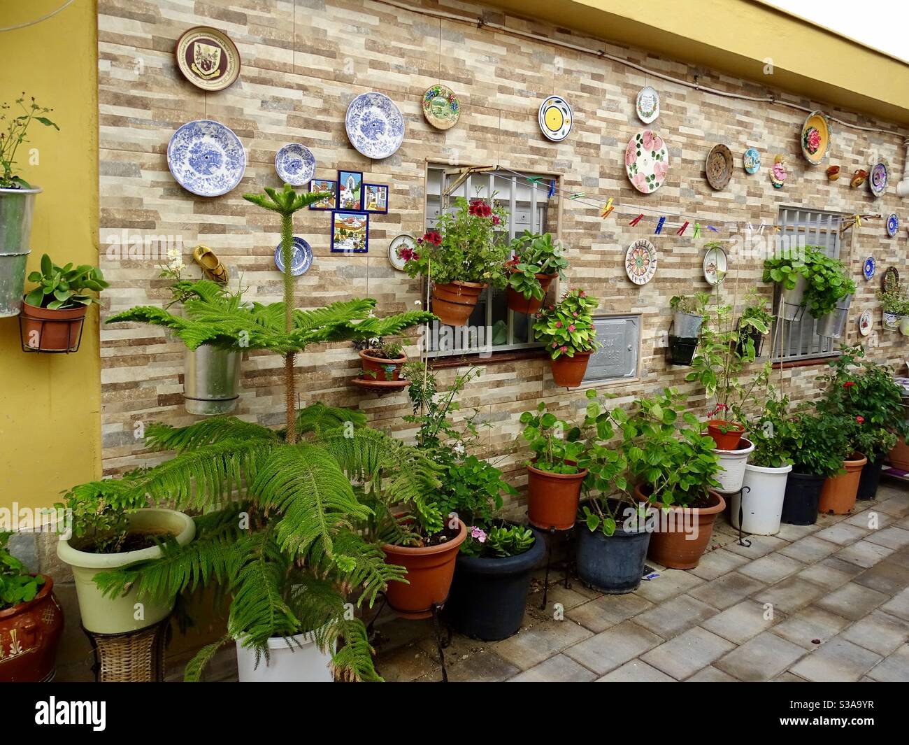 Piatti decorativi e vasi di fiori su un muro nel sud Spagna Foto Stock