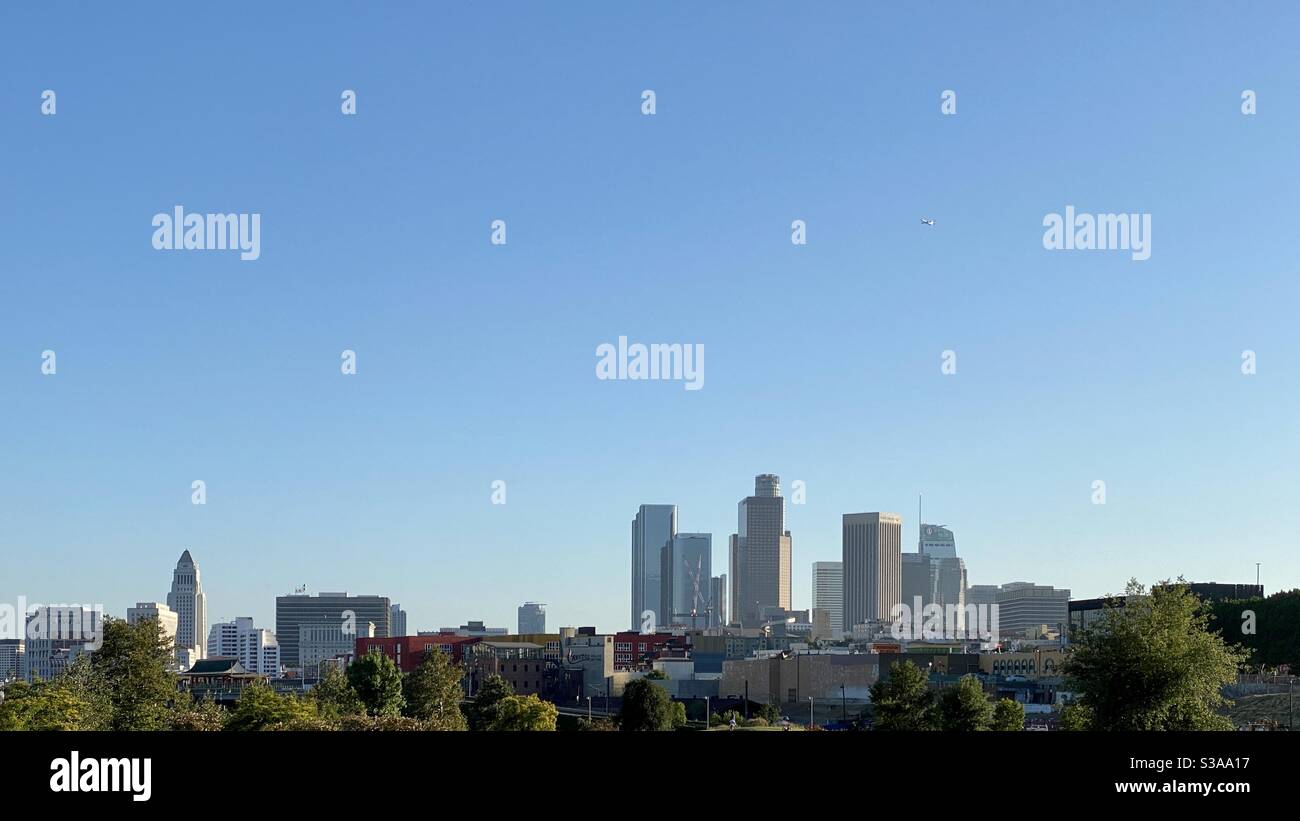 LOS ANGELES, CA, LUGLIO 2020: Skyline del centro con grattacieli nel quartiere finanziario sulla destra e Municipio sulla sinistra. Aereo che vola attraverso cielo blu in alto Foto Stock