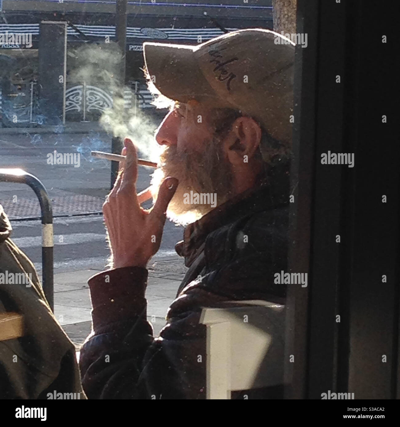 Uomo senza casa che fuma al sole Foto Stock