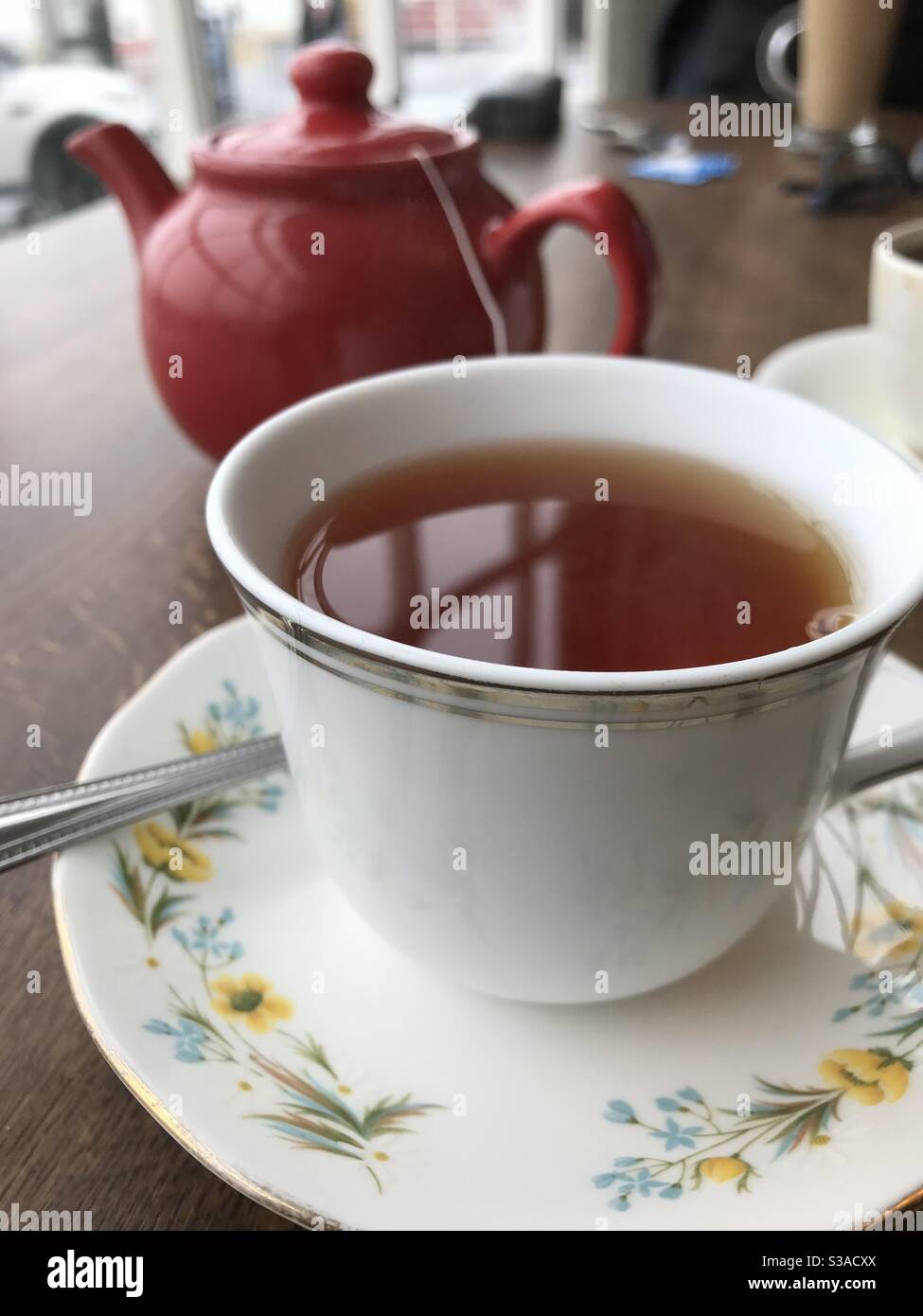 Tè Rooibos in una tazza bianca di Cina con il piattino e. teiera rossa - Immagine stock catturata con smartphone