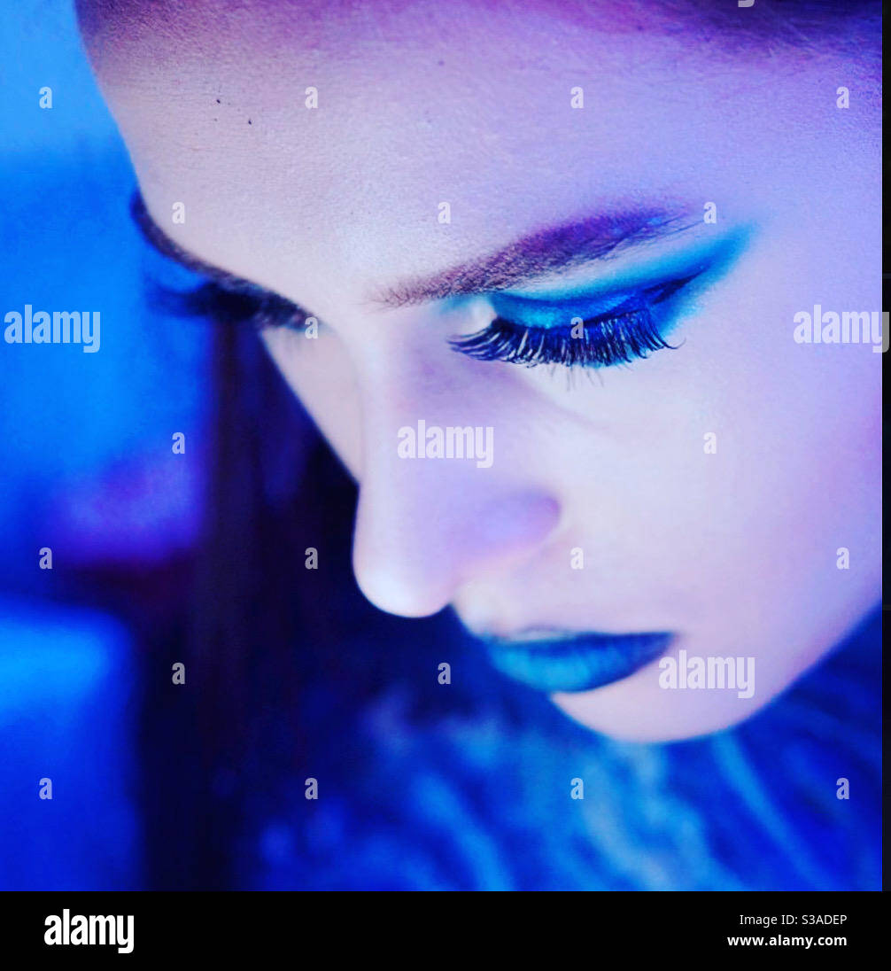 Giovane donna che guarda verso il basso. Futuristico blu compongono. Bellezza moderna - Immagine stock catturata con smartphone