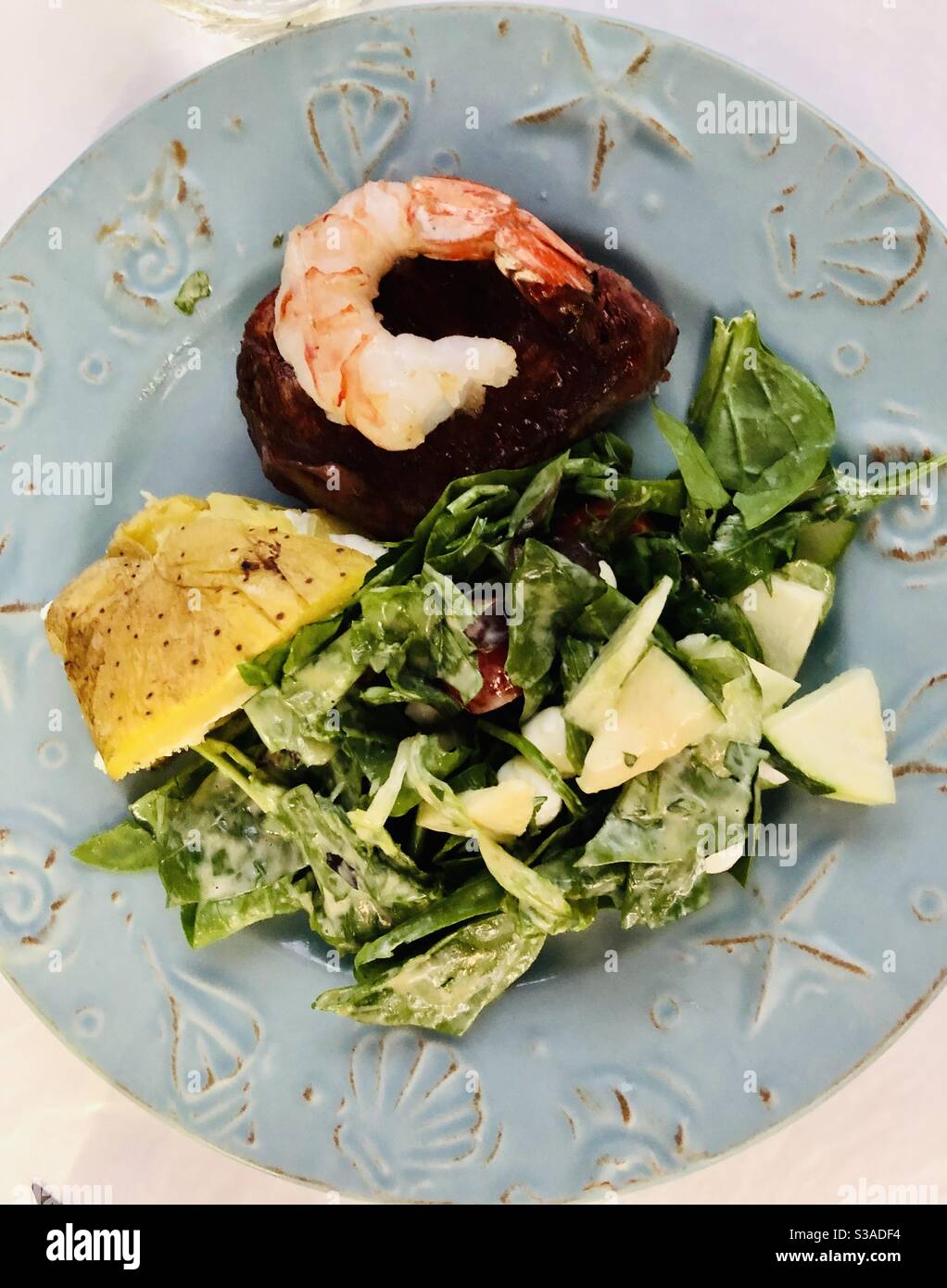 Piatto per la cena con insalata fresca, filetto mignon condito con un gamberetto alla griglia e un lato di patate al forno. Foto Stock