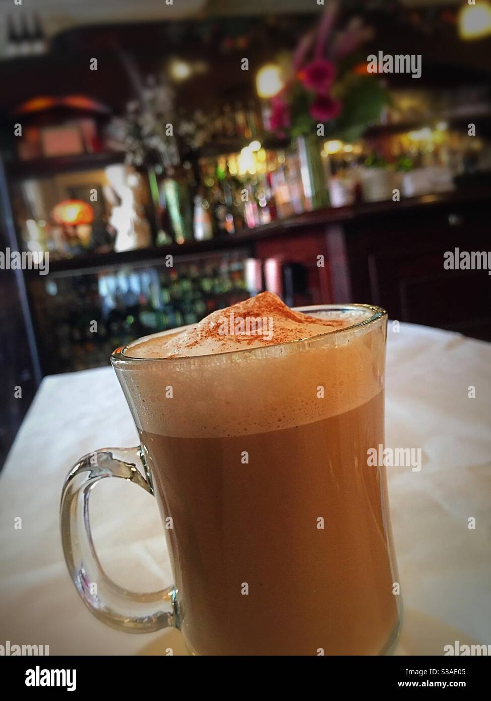 Cappuccino in una tazza di vetro trasparente servito in un elegante bistrot francese a Soho, New York City, USA Foto Stock