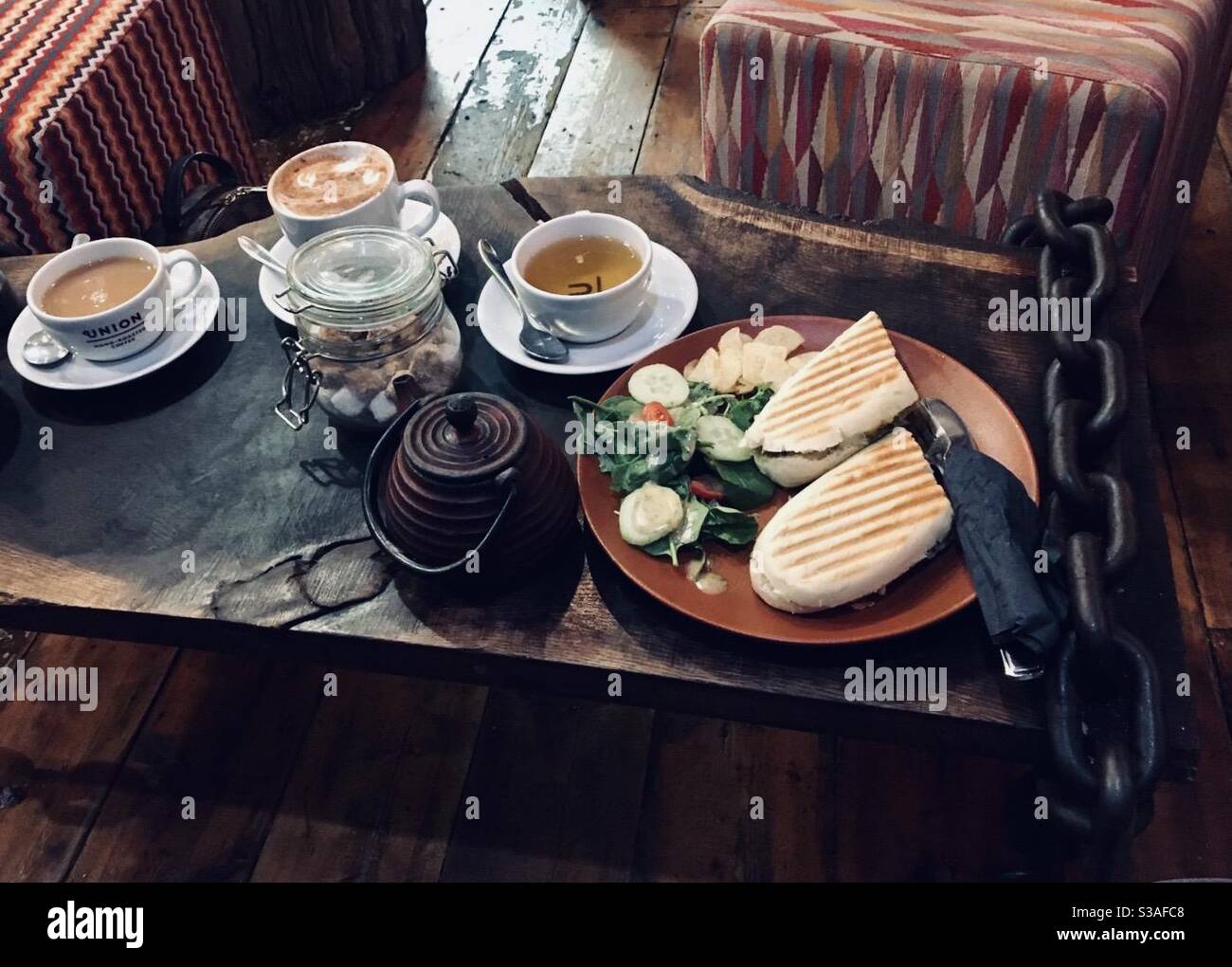 Panni con tè, teiera e selezione di caffè su un tavolo rustico. - Immagine stock catturata con smartphone