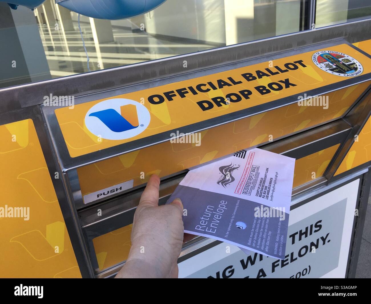 Una mano che rilascia un scrutinio per posta in una casella ufficiale della contea di Los Angeles alle elezioni del novembre 2020. - Immagine stock catturata con smartphone