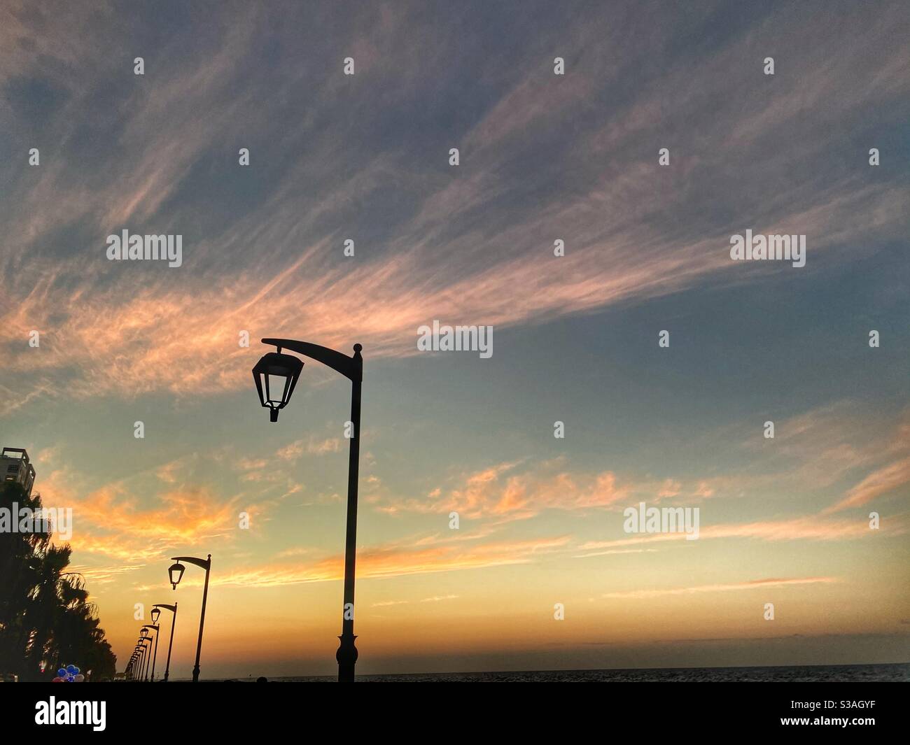 Passeggiata sulla spiaggia al bellissimo tramonto con prospettiva infinita di luci di strada Foto Stock