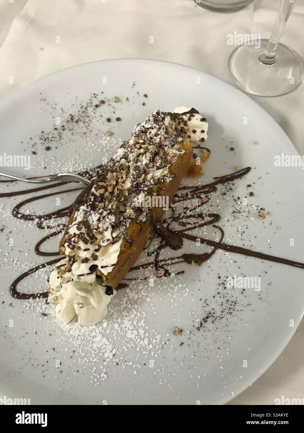 Una fetta di torta alla crema con un condimento al cioccolato - Immagine stock catturata con smartphone