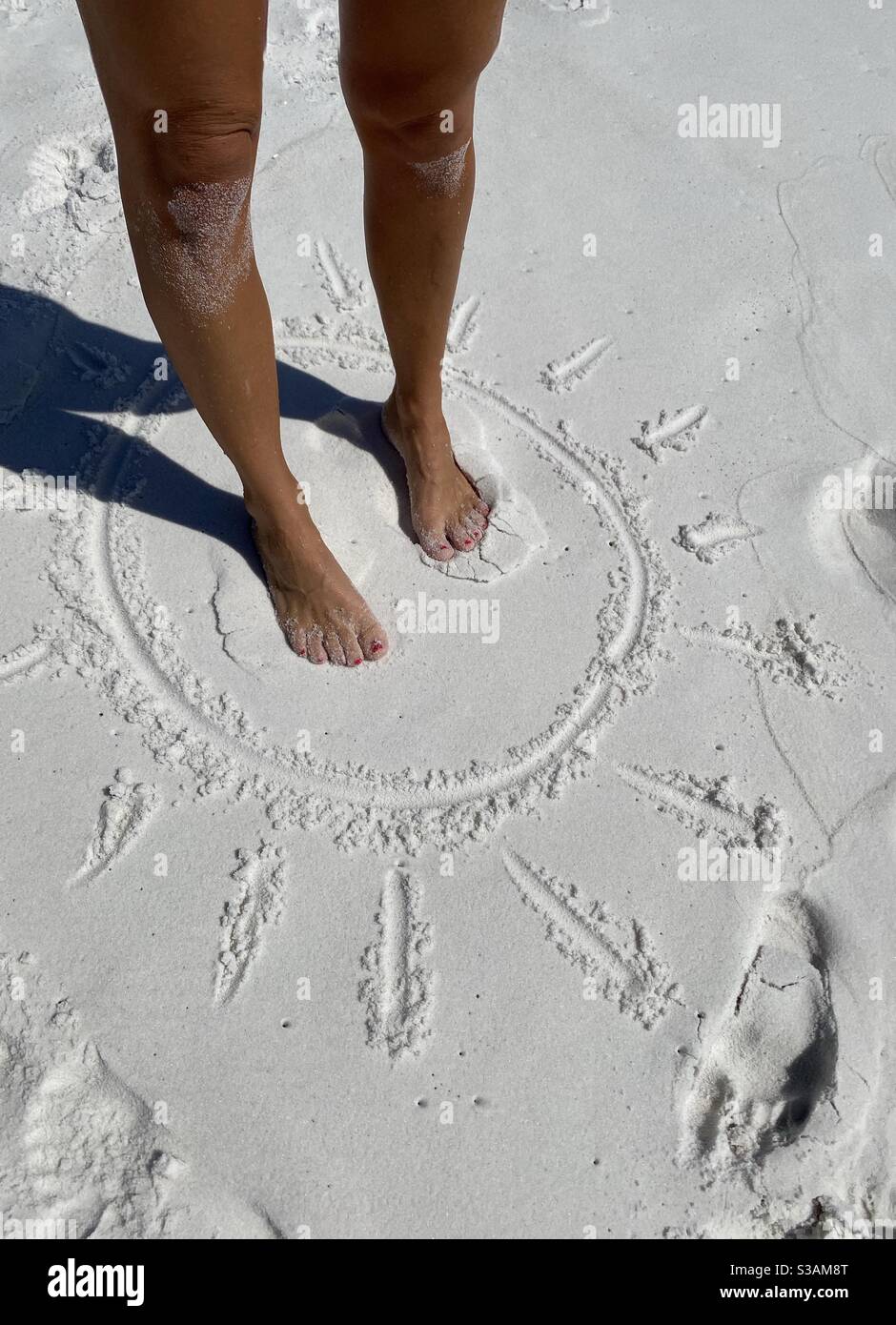 Tan gambe sabbiose in piedi in un sole tirato sul sabbia con l'ombra delle gambe Foto Stock