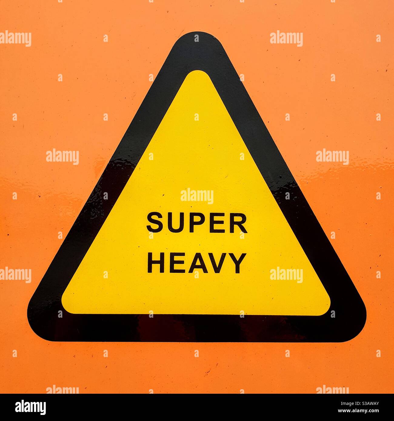 Un segnale di avvertimento giallo triangolare che informa il portatore di un peso super pesante sul lato di una spedizione industriale contenitore o vano di carico Foto Stock