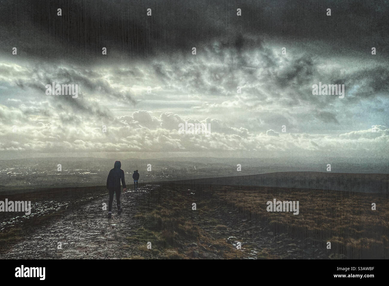 Due persone che camminano in condizioni umide sulla cima di Pendle Hill nel Lancashire Foto Stock