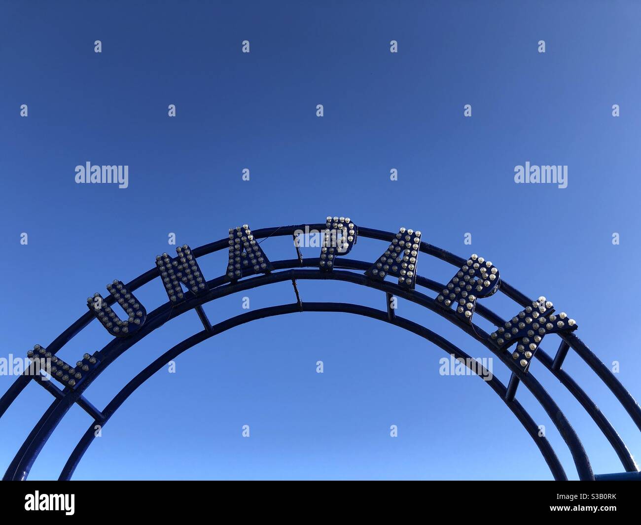 Segno curvo pubblicità Luna Park a Scarborough, Inghilterra, UK con cielo blu chiaro - Immagine stock catturata con smartphone