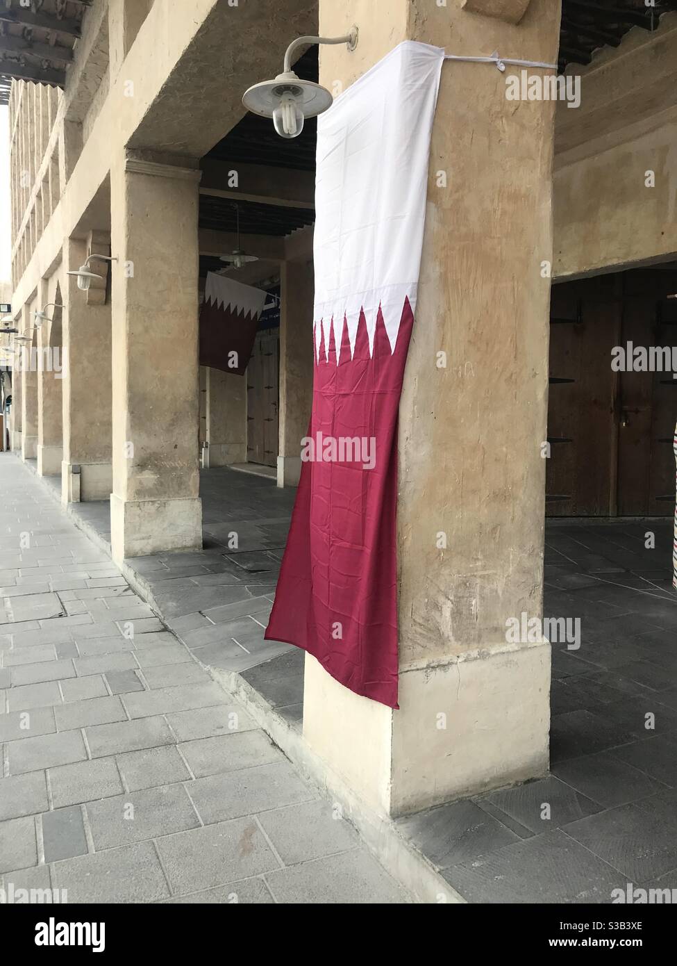 Bandiera Qatar appesa al di fuori di un negozio a Souk Waqif, Doha, Qatar - Immagine stock catturata con smartphone