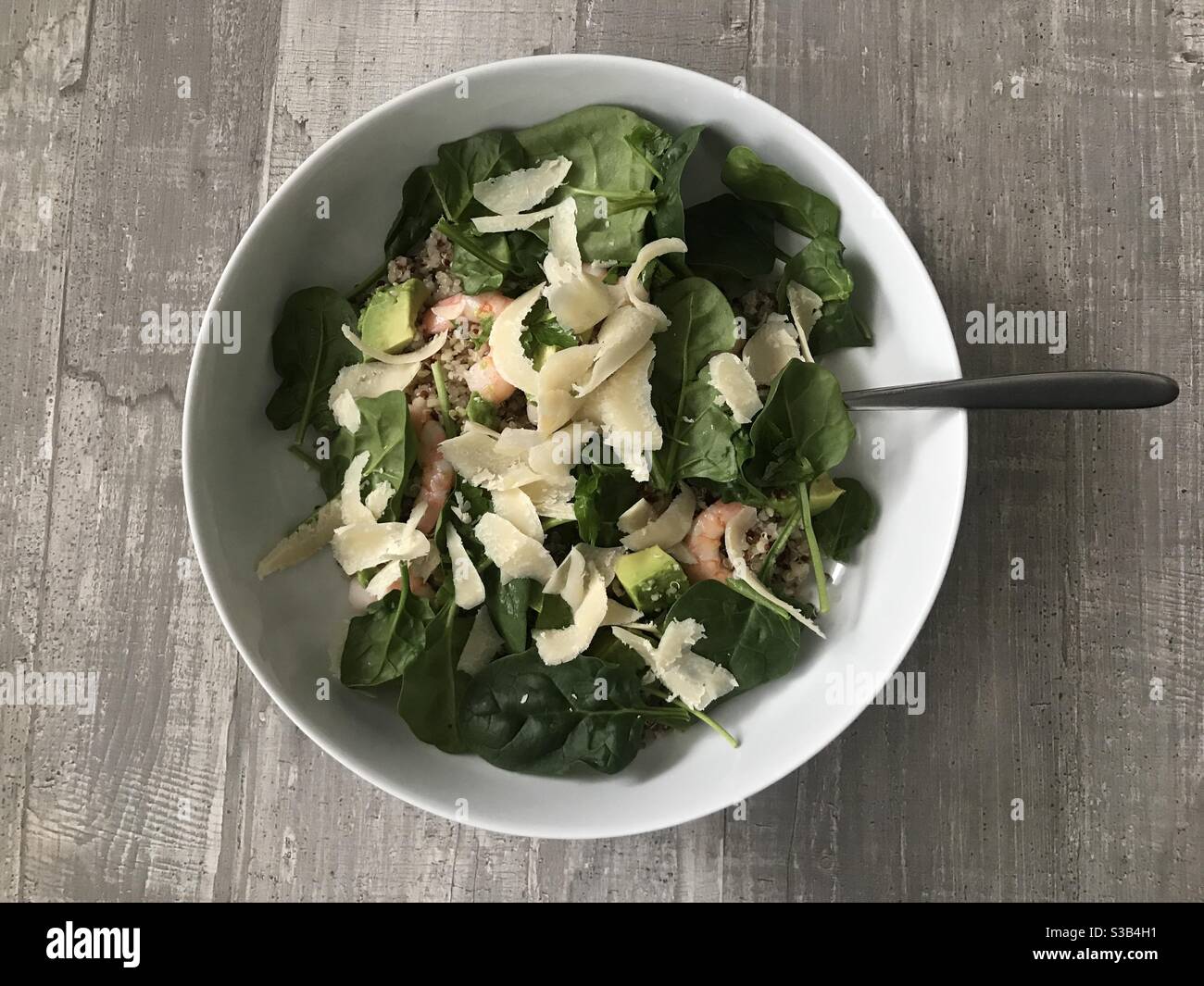 Quinoa, gamberi, avocado e insalata di spinaci con scaglie di parmigiano su fondo ligneo Foto Stock