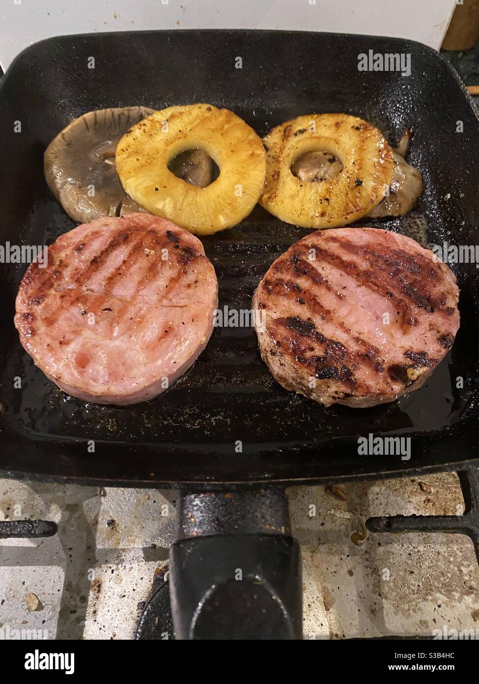 Novembre 2020 - cottura alla griglia mista, due bistecche di gammon, con grandi anelli di funghi e ananas - Immagine stock catturata con smartphone