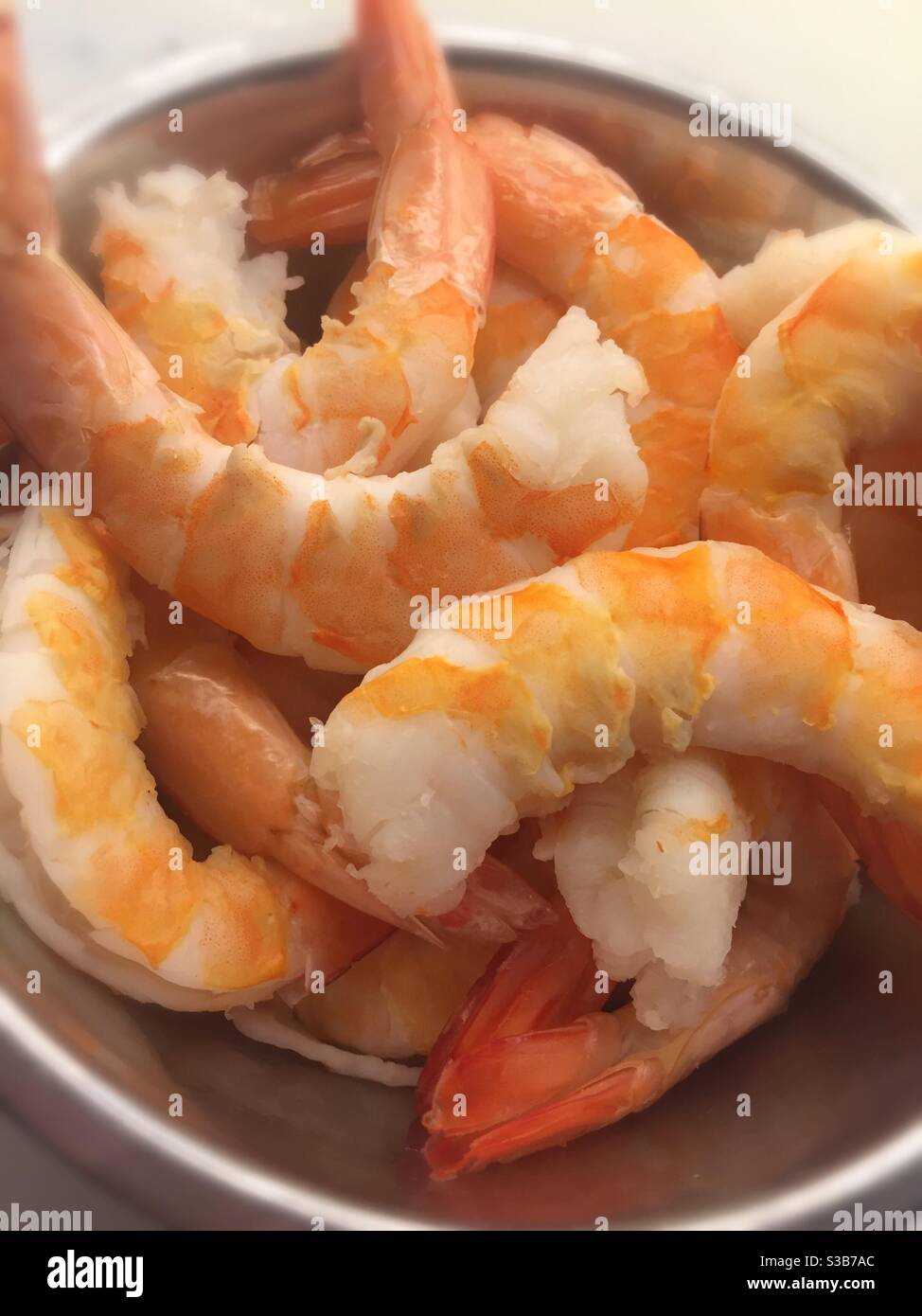 Gamberi jumbo cucinati e puliti in una ciotola di metallo sul banco della cucina, primo piano Foto Stock