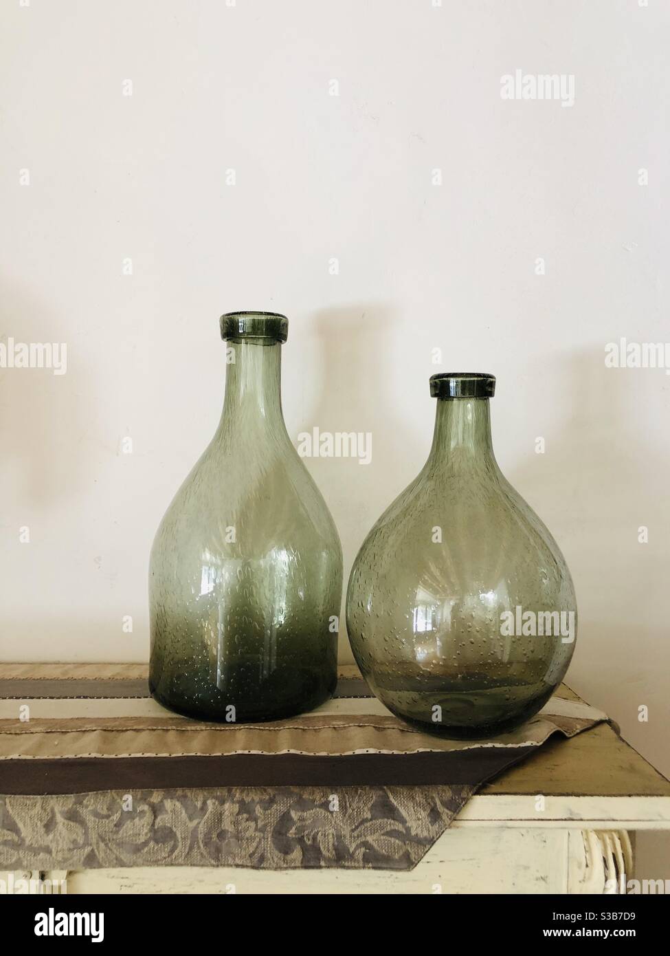 Due vecchie bottiglie di vetro sopra un armadietto di legno Foto Stock