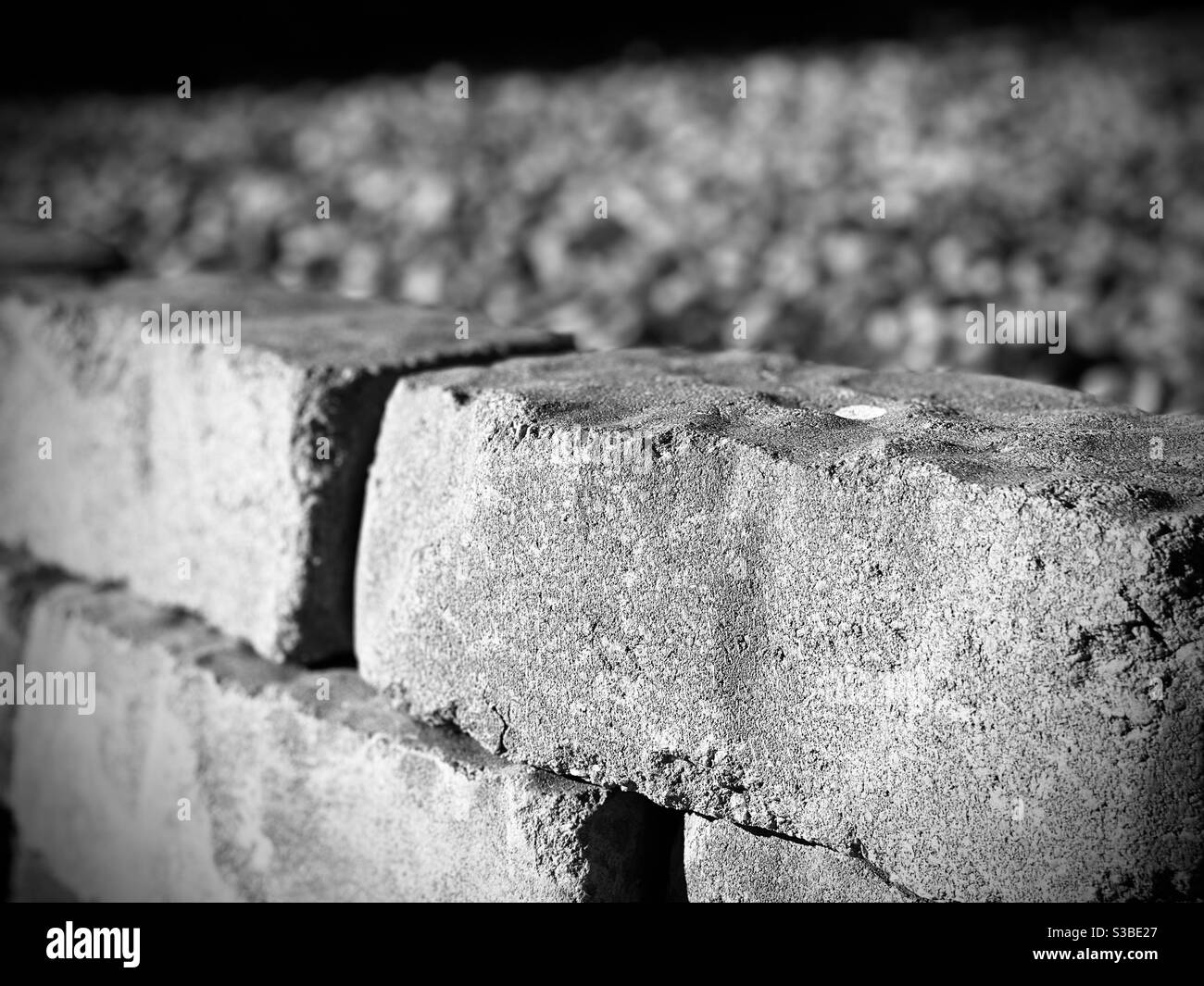Mattoni, eventualmente disposti in un muro o in una pila, che si affaccia su pietre più piccole. Preso in nero e bianco. Foto Stock
