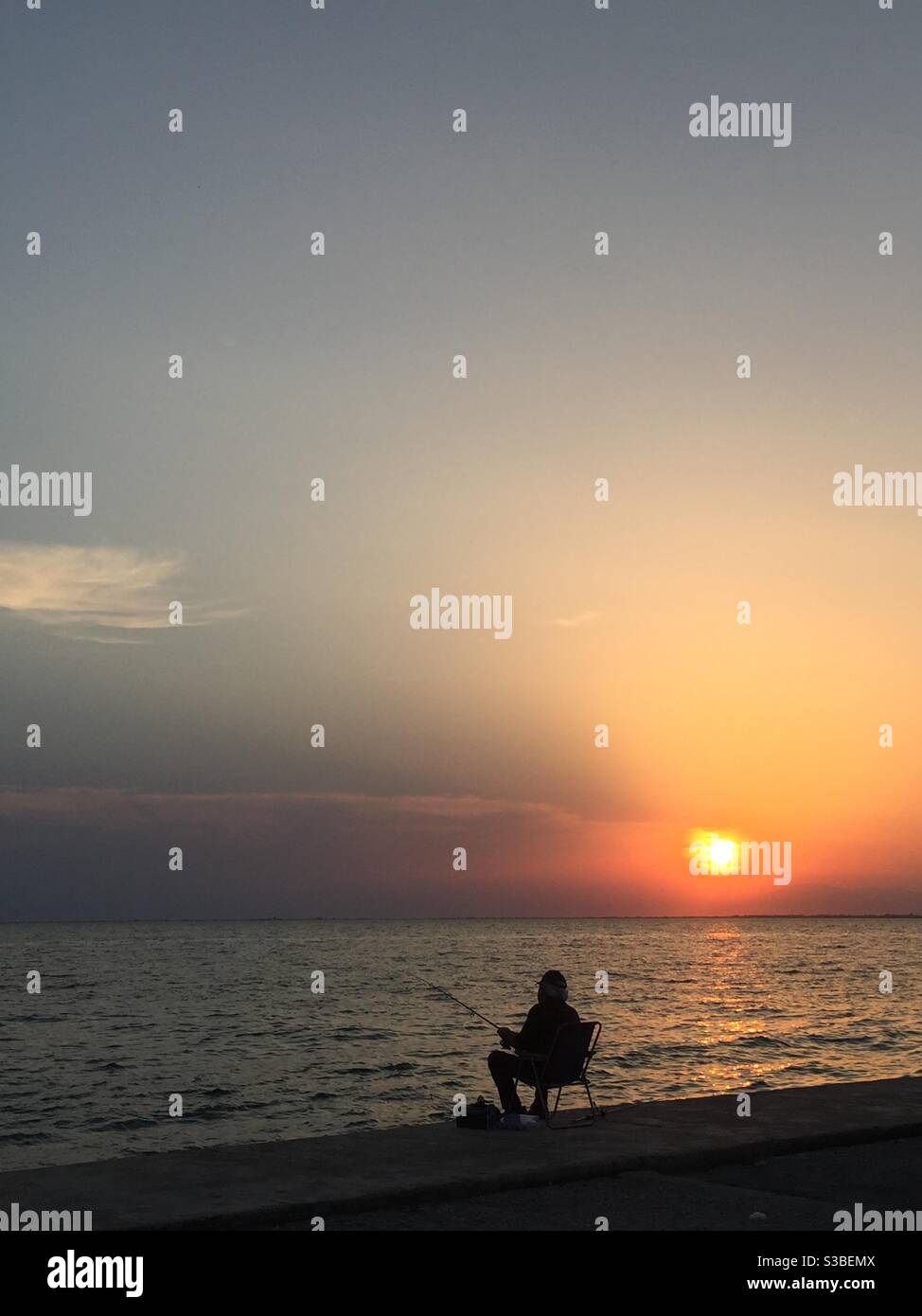 Pesca dell'uomo durante il tramonto a salonicco. Foto Stock