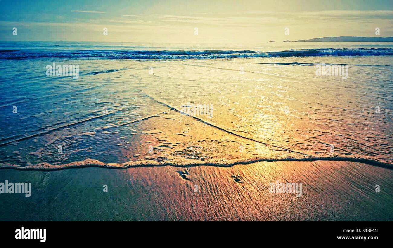 Una fotografia di piccole onde che lambisce su sabbia liscia. Splendido paesaggio tranquillo sulla spiaggia Foto Stock