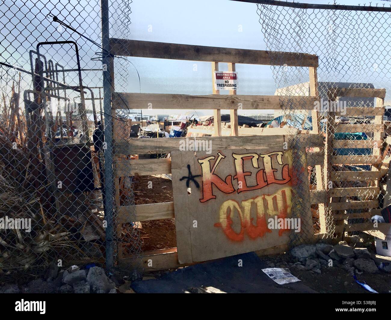 Campo senza dimora recintato dipinto a mano che dice "Keep out" a West Oakland, California, USA. - Immagine stock catturata con smartphone