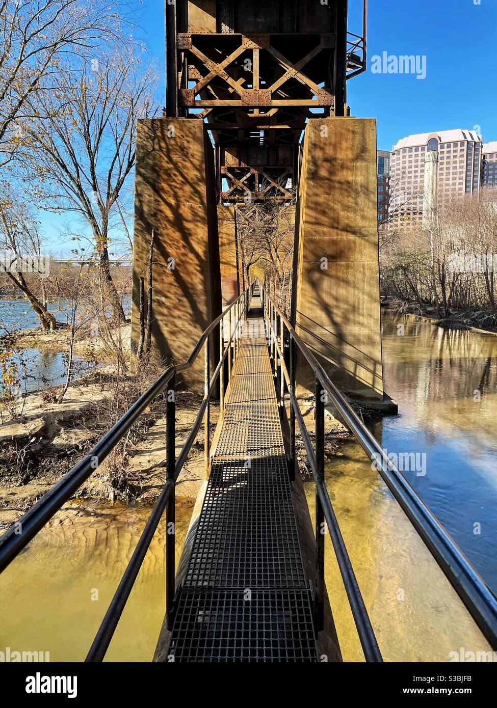 Una passerella in acciaio su un fiume lungo una pista ferroviaria. Foto Stock