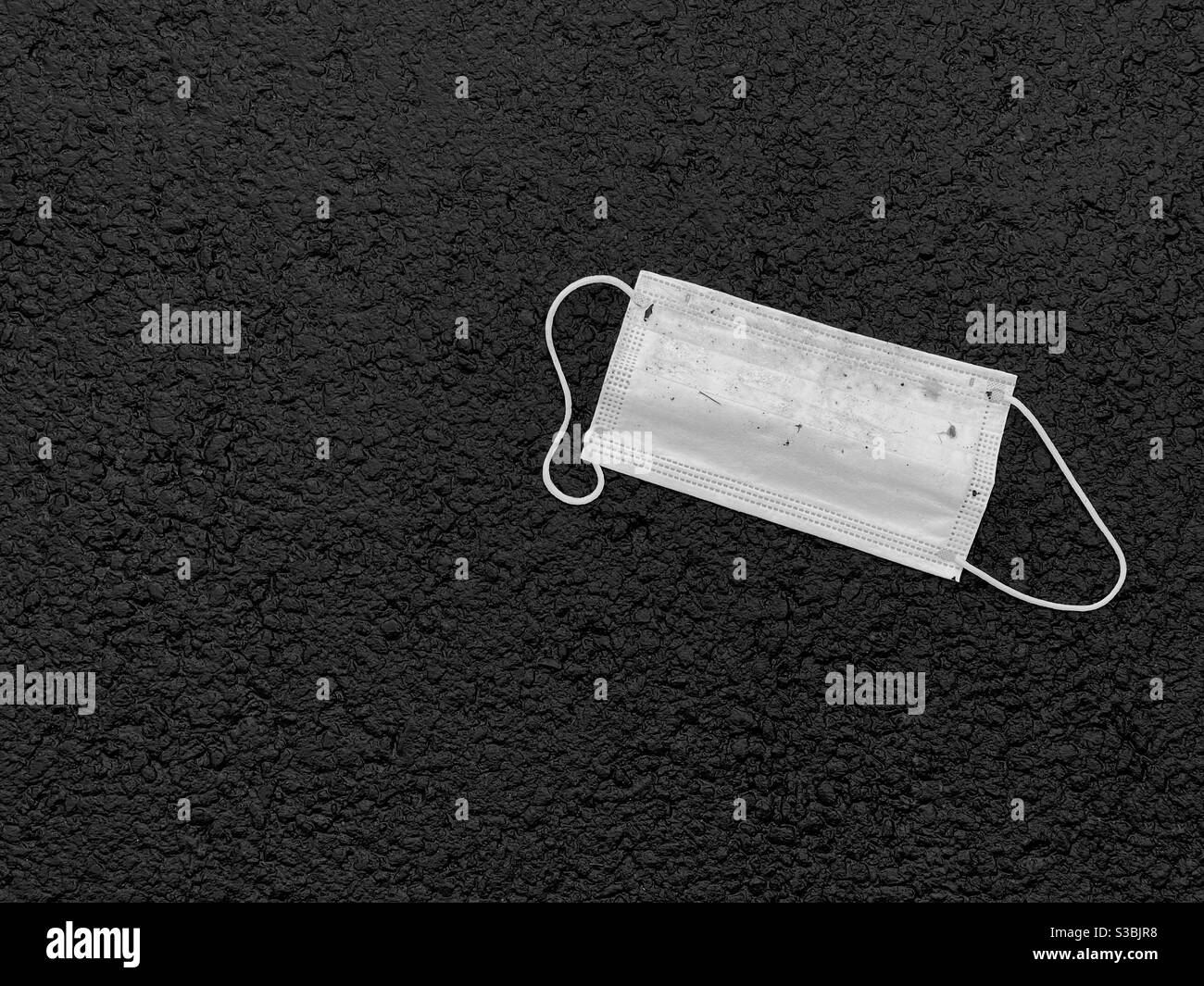 Maschera di plastica usata gettata su un pavimento. Nessuna gente. Spazio di copia. Foto Stock