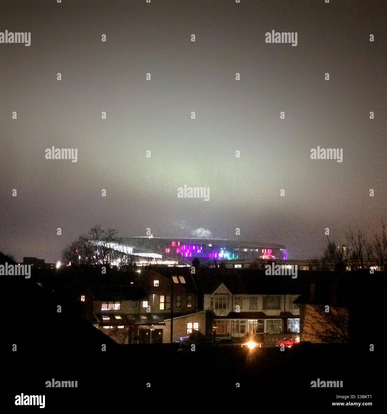 Lo stadio di calcio Tottenham Hotspur si è illuminato in una notte di inverni il giorno della partita, visto dalle strade circostanti - Immagine stock catturata con smartphone