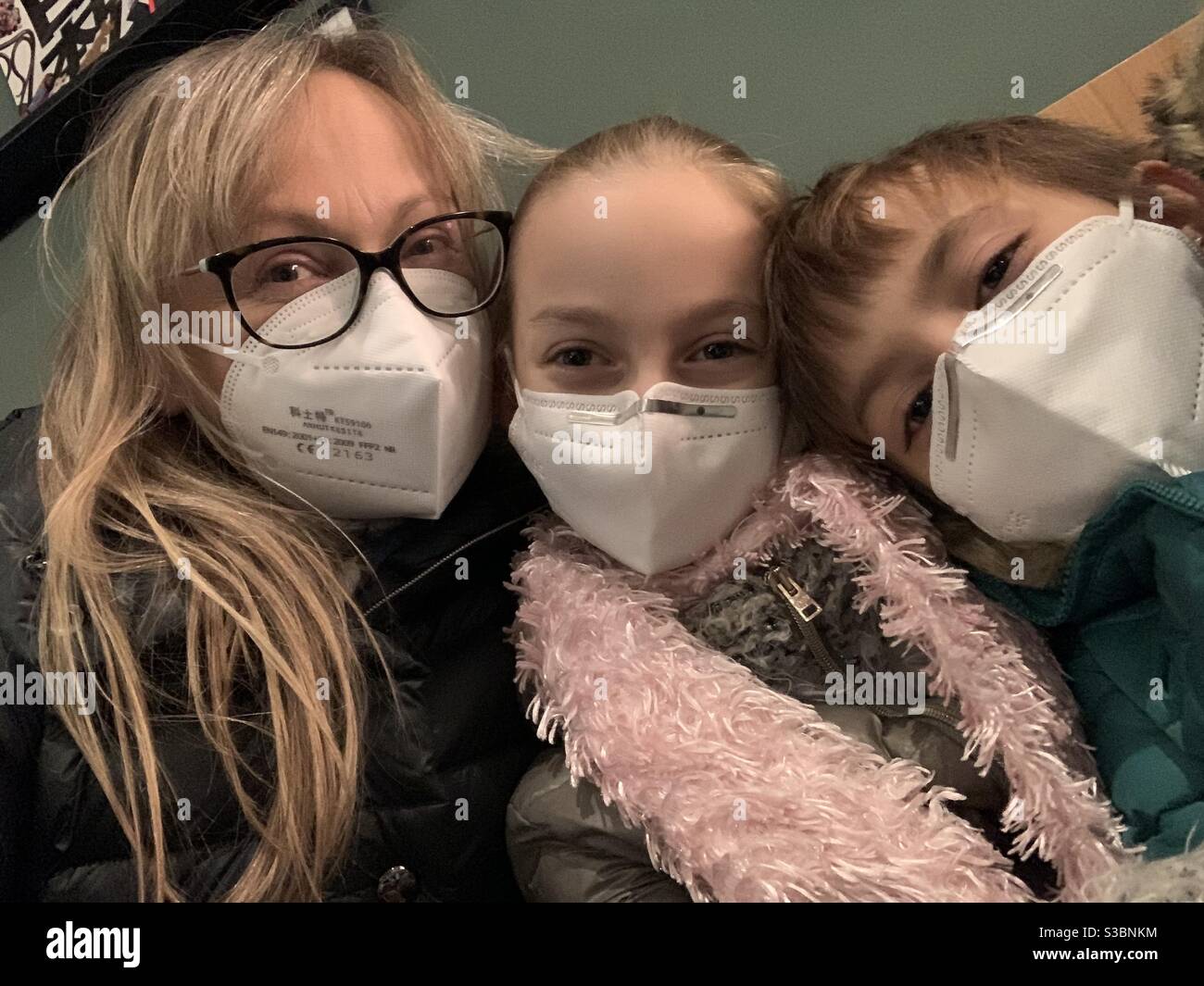 Madre e figlie che indossano maschere facciali. Foto Stock