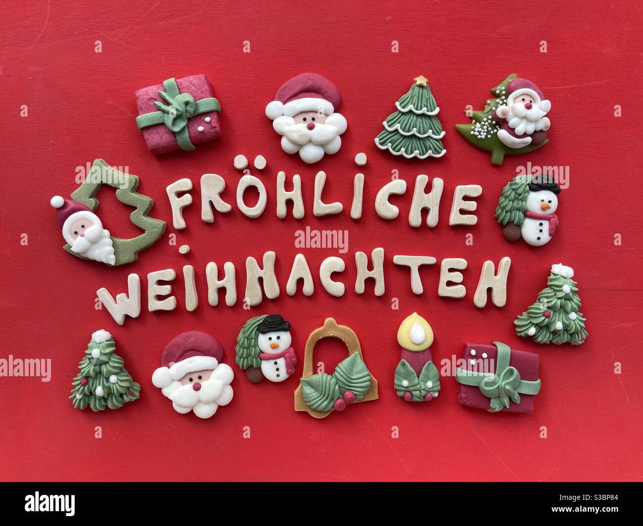 Fröhliche Weihnachten, buon Natale in lingua tedesca con lettere in legno e marzapane simboli di Natale Foto Stock