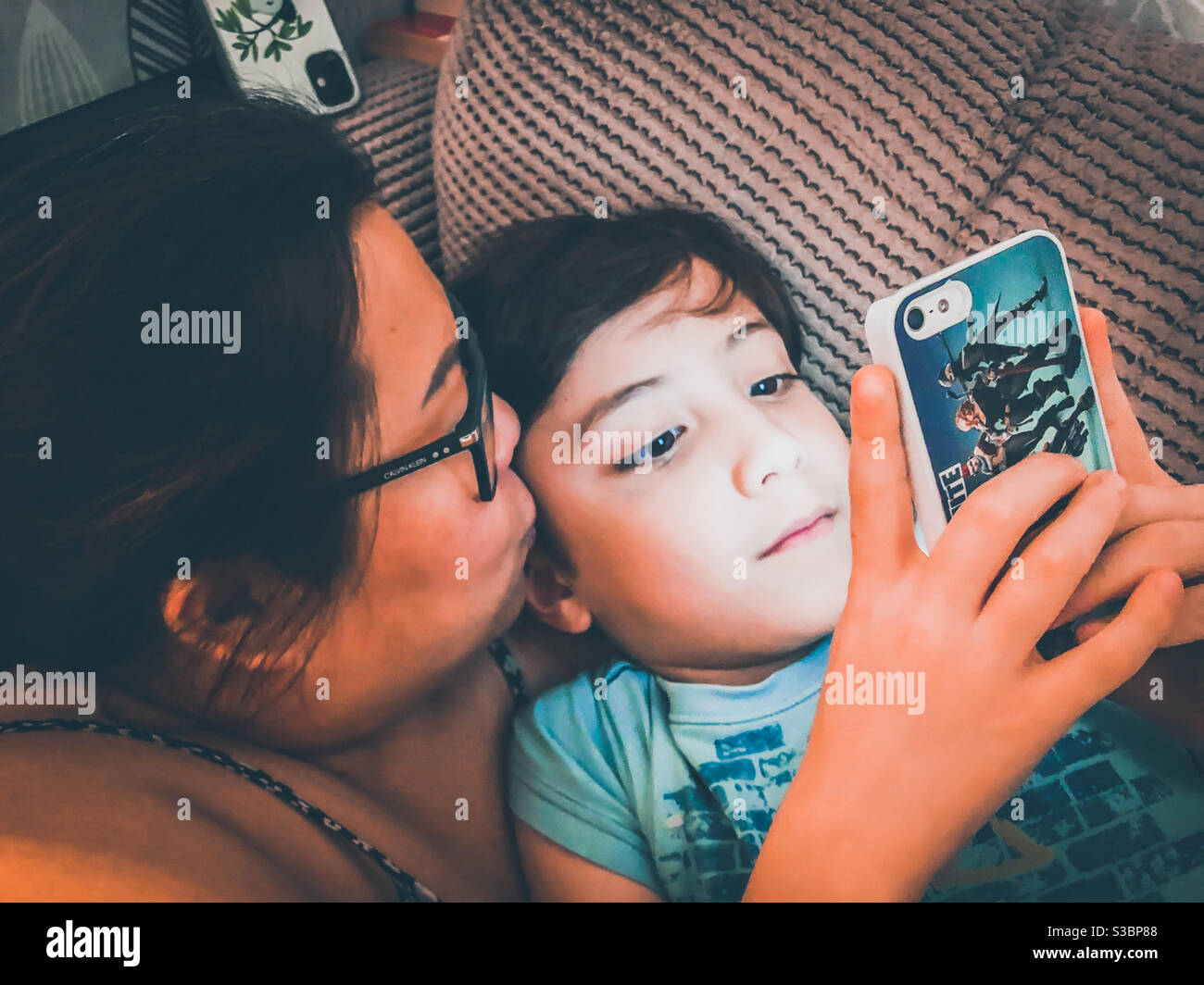 Madre e figlio coccolano e guardano insieme un video clip su uno smartphone. Foto Stock