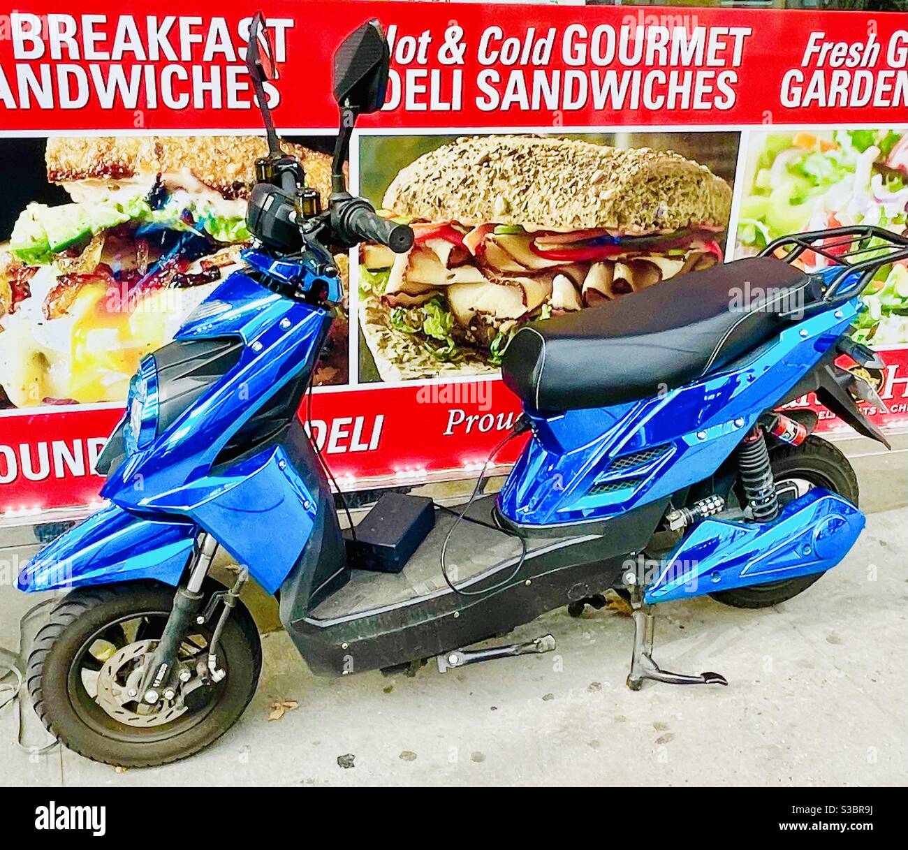 Parcheggiata sul marciapiede presso un deli Third Avenue nel quartiere Murray Hill di Manhattan, NY, USA, è una moto personalizzata blu brillante Foto Stock