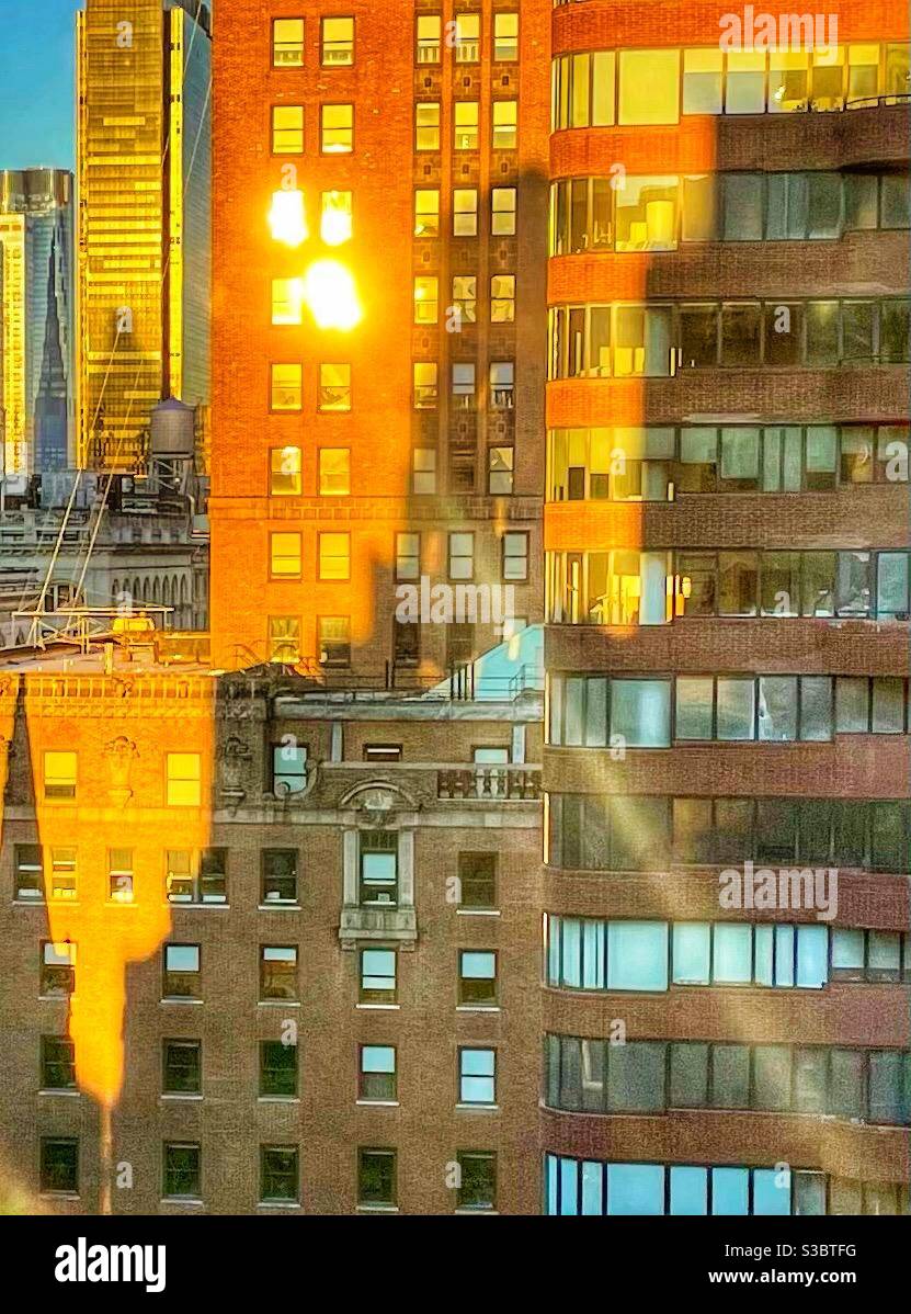 Il fascio di sole del mattino si riflette nella finestra di un alto edificio di New York nel centro di Manhattan. - Immagine stock catturata con smartphone