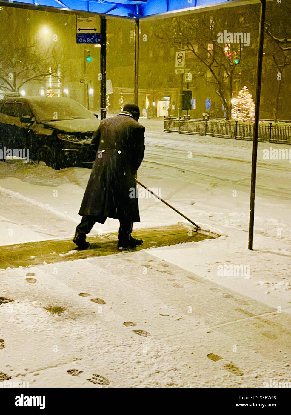 Il portiere notturno solista libera la neve dal marciapiede al 30 Park Avenue mentre una tempesta di neve inizia a New York City. Foto Stock