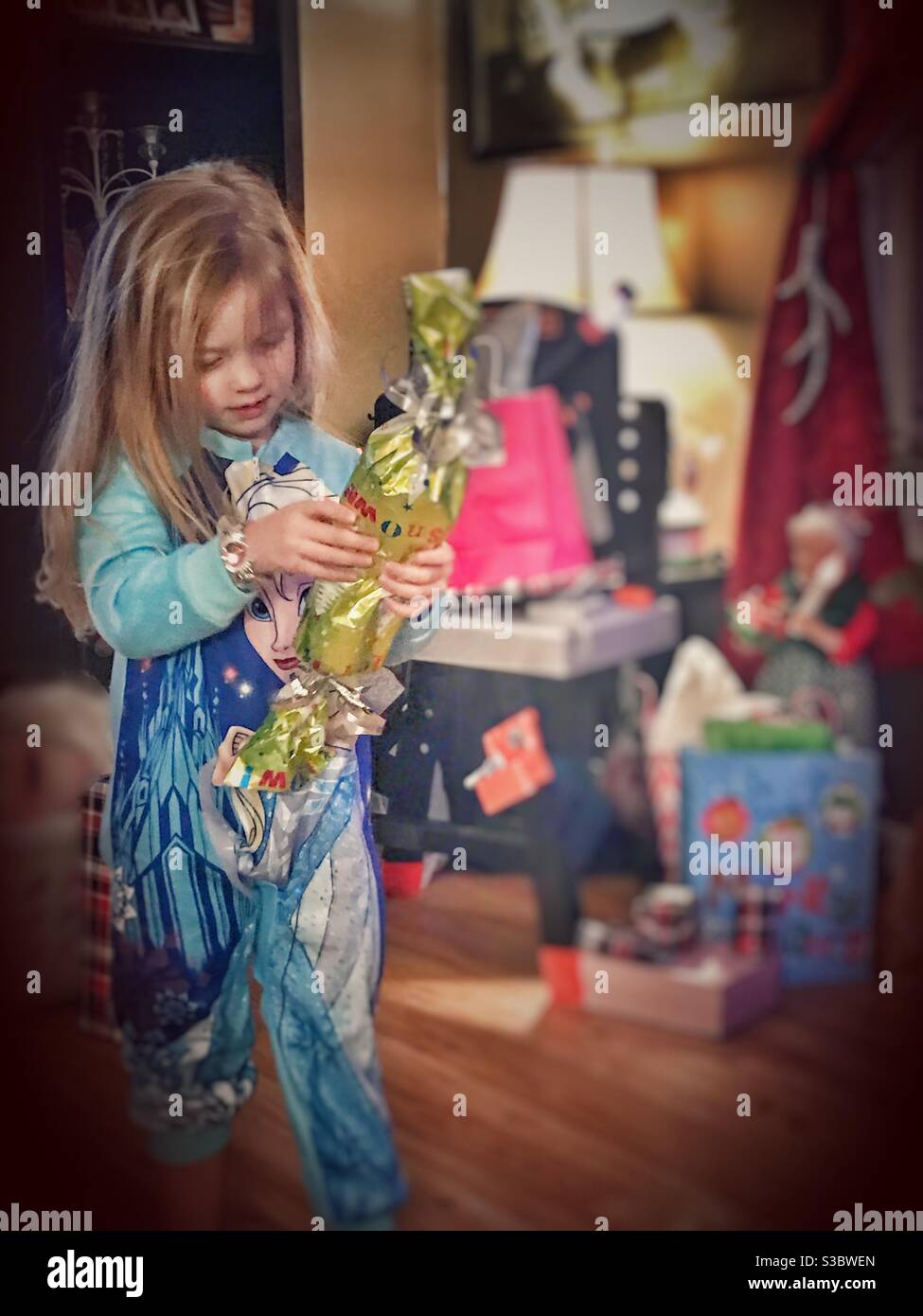 Bambina che indossa pigiami surgelati con Elsa che apre un Natale presente Foto Stock