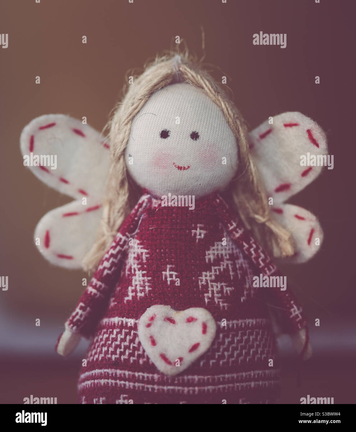 Un angelo peluche con felice volto sorridente e amorevole cuore - Immagine stock catturata con smartphone