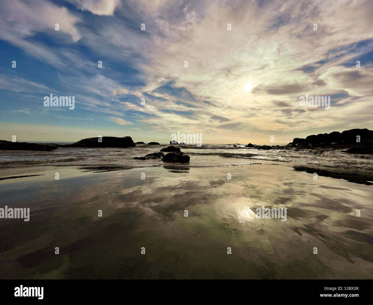 Mare con cielo drammatico che si riflette sulla sabbia bagnata. Foto Stock